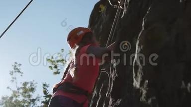 <strong>坚强</strong>的年轻女孩努力攀岩。 夏天在户外运动。